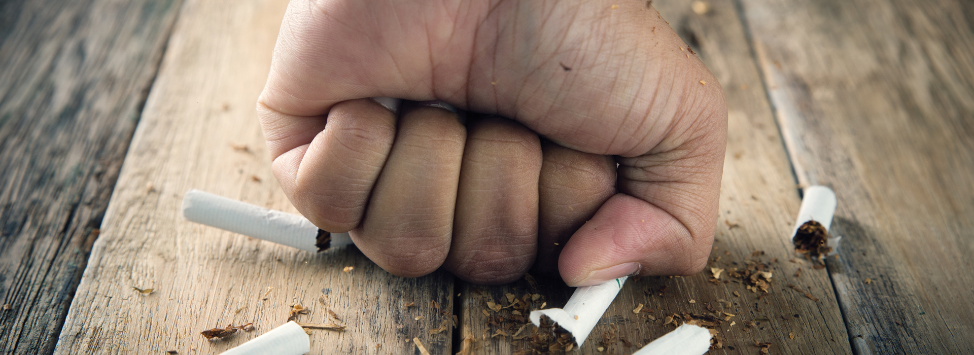 person smashing a cigarette with their fist