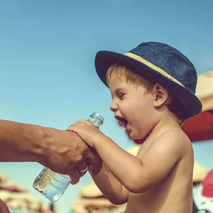 child drinking water on the beach