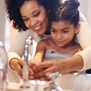 woman helping child wash hands
