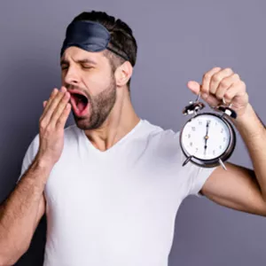 man yawning holding a clock