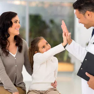 little girl giving a high five to her doctor as her mother observes