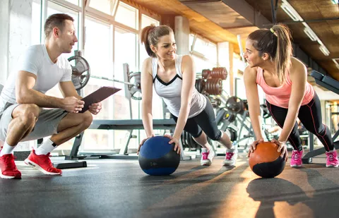 young people working out at gym with a trainer.