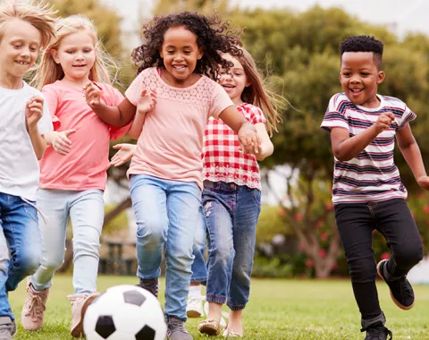 happy smiling children playing soccer outside