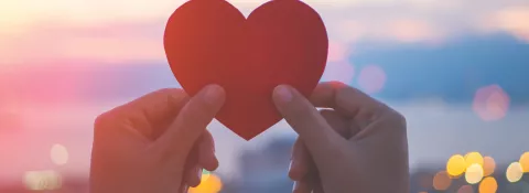 someone holding a heart shaped piece of paper 