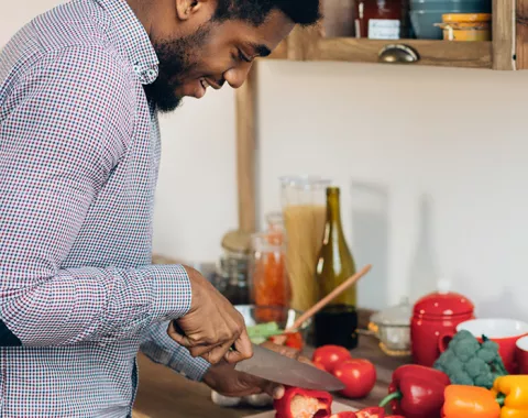 Young man chopping vegetables in kitchen