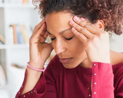 Young woman with headache holding her temples